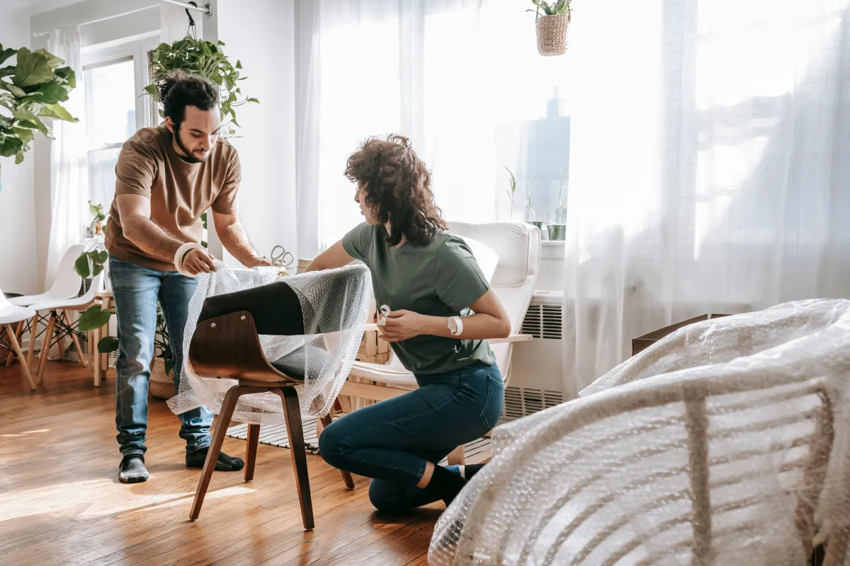 A couple wrapping a chair together while preparing to move